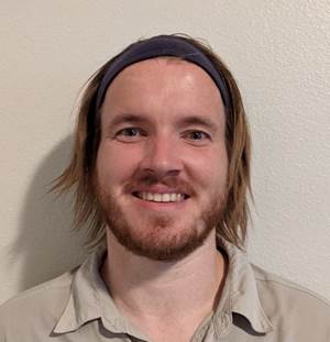 A person with a beard and mustache smiling

Description automatically generated