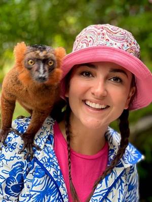A person with a lemur on her shoulder

Description automatically generated
